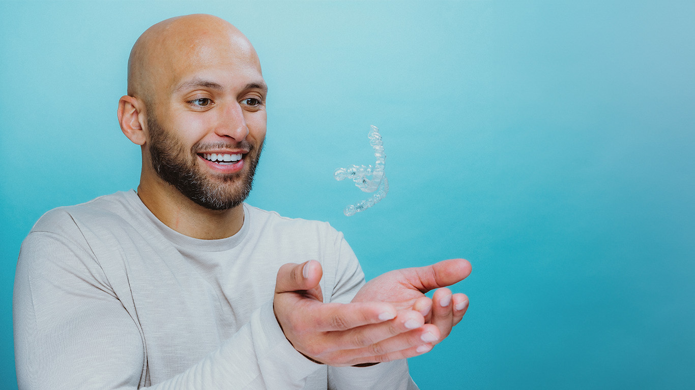 Patient holding clear aligner retainer — Stay Aligned subscription